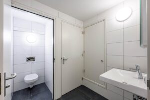 Moderne, wit betegelde toiletruimte met hangtoilet en fonteintje op de Prins Hendrikkade.